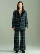 Pantalón de tiro alto con corte ancho y recto, confeccionado en tela de algodón con estampado de cuadros escoceses en tonos azul marino, verde y rojo. Presenta cierre frontal oculto con botones internos y pasacintos en la cintura.