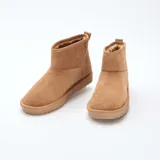 Botas cortas de estilo casual en color marrón, confeccionadas en ante sintético con interior forrado en piel sintética para mayor calidez. Presentan una suela plana de goma con relieve dentado y un tirador en la parte trasera.