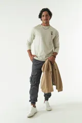 Pantalón cargo gris con puños elásticos, corte regular, bolsillos laterales con solapa y pasacintos.