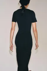 Vestido largo negro de punto con cuello redondo, manga corta y bajo con tejido combinado semitransparente.