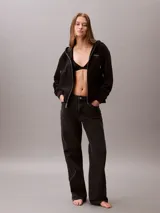 Buzo con capucha y cierre frontal de cremallera de la marca Calvin Klein, color negro, de corte regular cropped y manga larga. Presenta bolsillos tipo canguro, cordones ajustables en la capucha y el logo monograma de la marca estampado en el pecho.