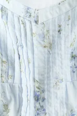 Top de algodón color celeste con estampado floreado, escote corazón y mangas con volados. Presenta detalles de jaretas frontales y corte peplum con vuelo en la parte inferior.