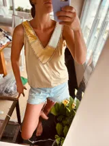 Musculosa dorada con apliques de cuero en forma de V en color blanco, amarillo y marrón.