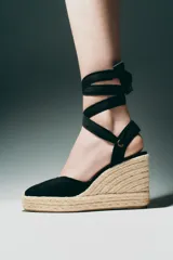 Zapato destalonado con tacón tipo cuña, color negro, con combinación de materiales en el corte y tiras para atar en el tobillo.