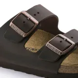Sandalias Birkenstock modelo Arizona, color marrón oscuro, con doble tira ajustable con hebillas metálicas y plantilla anatómica de corcho.