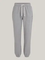 Pantalón de jogging gris de felpa de algodón, con cintura elástica ajustable con cordón, dos bolsillos laterales, un bolsillo trasero y bajos elásticos. Presenta el logo de Tommy Hilfiger bordado en el lateral.