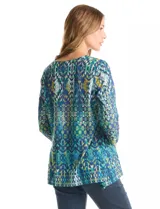 Blusa de calce relajado con estampado geométrico multicolor en tonos azules, verdes y amarillos. Presenta escote redondo con detalle tejido en el contorno, mangas tres cuartos y silueta levemente evasé.