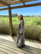 Vestido largo color verde oliva, de lino, con corte amplio, cuello mao, escote en V y mangas largas acampanadas.