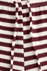 Pantalón de punto suave, de piernas amplias y corte holgado, con diseño a rayas horizontales en color bordó y blanco. Cuenta con cintura elástica y cordón ajustable.