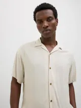 Camisa de manga corta con cuello resort, confeccionada en viscosa fluida con cierre frontal de botones y corte relajado.