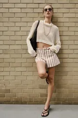 Shorts de denim de tiro bajo con diseño de rayas verticales en tonos rosado y marrón, cinco bolsillos, cierre frontal con cremallera y botón, y detalle de cintura desflecada.