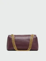 Cartera Marc Jacobs modelo The Puffy Smooth Dual Chain Mini Bag, confeccionada en cuero liso de color bordó, con diseño acolchado y solapa frontal. Cuenta con cierre de broche metálico dorado y correa de cadena metálica doble.