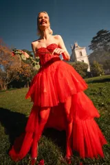 Vestido de fiesta rojo de tul con corpiño strapless de encaje y falda asimétrica de varias capas.
