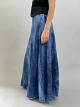 Falda larga de jean denim con efecto de lavado ácido y diseño de paneles geométricos cosidos. Presenta cintura alta, cierre lateral invisible y bolsillos ocultos, con un corte acampanado que aporta volumen y movimiento.