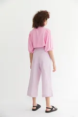 Pantalón culotte de lino color lila, tiro alto, con detalle de lazo ancho en la cintura y corte ancho que termina a media pierna.