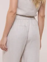 Pantalón wide leg de lino color beige, con silueta amplia, pretina con pasacintos, bolsillos laterales con detalles bordados a contraste y ruedo ancho.