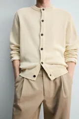 Cardigan de punto en hilatura de algodón y lino, con ajuste regular, cuello redondo, manga larga y acabados en rib. Presenta cierre frontal de botonadura con botones oscuros.