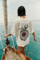 Remerón blanco de algodón con estampa de brújula con un corazón rojo en el centro, la frase "Mystical Voyage" y la firma "By Renée".