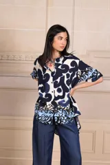 Camisa de manga corta con estampado abstracto en tonos azul marino, azul claro y blanco, y un patrón floral en el dobladillo.