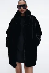 Abrigo de Zara con efecto pelo, cuello de solapa con muescas, manga larga y bolsillos delanteros. Cuenta con forro interior a tono y cierre frontal mediante ganchos metálicos.