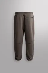 Pantalón jogger relaxed fit Zara Athleticz de tejido técnico compacto elástico con mezcla de algodón. Presenta cintura elástica ajustable con cordón, bolsillos laterales en la cadera, bolsillo trasero con cierre de cremallera, bajo ajustable con elástico y detalle de logo estampado en la pernera.