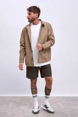 Cazadora color beige con cuello clásico, cierre frontal con botones, mangas largas y bolsillos de parche en el pecho.