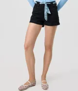 Short de jean negro de tiro alto con bolsillos delanteros y traseros, cierre con botón y cremallera, e incluye un pañuelo celeste con lunares y ojales metálicos para usar como lazo en la cintura.