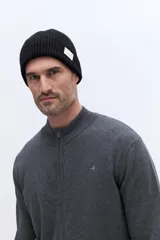 Campera de tejido de punto liviano color beige, con cierre frontal completo y cuello alto tipo bomber. Presenta un pequeño logo bordado en el pecho y puños acanalados.