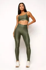 Calza deportiva color verde militar, de tiro alto con cintura en forma de V, confeccionada en tejido brillante con textura acanalada.