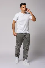Pantalón jean gris claro, estilo jogger, con bolsillos cargo laterales y puños elásticos en los tobillos.