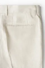 Pantalón de traje de corte ajustado confeccionado en lino liviano. Presenta cierre con corchete oculto, raya marcada en las piernas, bolsillos laterales y bolsillos traseros ribeteados.