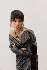 Chaqueta negra de cuero con cuello camisero, mangas largas y costuras decorativas.