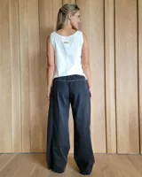 Pantalón de algodón color arena, de corte recto y holgado, con cintura elástica y detalle de costuras horizontales decorativas en la parte inferior de las piernas.