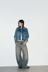 Jeans de tiro bajo con corte baggy y silueta barrel. Presenta diseño de cinco bolsillos, trabillas para cinturón y cierre frontal con cremallera y botón metálico. Confeccionado en denim con efecto de lavado desgastado.