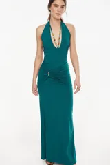 Vestido largo color verde oscuro, de corte entallado y silueta fluida, con escote halter pronunciado y detalle fruncido en la cintura.