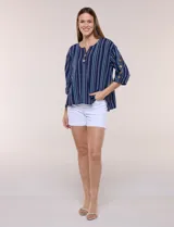 Blusa Erika de algodón con estampado de rayas en tonos azules, rosados y amarillos. Presenta cuello redondo con escote en V y botones frontales, mangas cortas decoradas con una fila de botones en los laterales y dobladillo asimétrico.