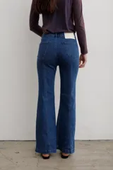 Jean de denim azul de tiro medio, con corte flare y costuras frontales destacadas.
