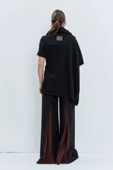 Poncho asimétrico de tejido de punto en color marrón, con cuello alto tipo polera y diseño sin mangas con aberturas laterales.