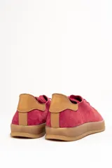 Zapatilla de cuero vacuno color rojo, con cordones al tono y suela de caucho color caramelo. Detalle de cuero vacuno color tostado en el talón.