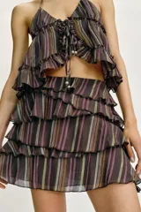 Falda pantalón corta con diseño de volantes superpuestos, confeccionada en tejido estampado a rayas con hilos metalizados. Cuenta con forro interior y cierre lateral con cremallera oculta.
