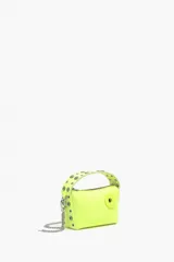 Bolso bandolera tipo hobo de piel color amarillo flúor, tamaño mini, con cierre de cremallera, asa de mano con apliques de caritas sonrientes y asa bandolera metálica extraíble.