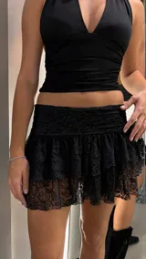 Minifalda short negra de encaje con volados y tiro bajo.