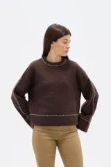 Sweater negro de corte holgado con cuello redondo a la base y detalle de costuras decorativas en contraste a lo largo de las mangas y el cuello.