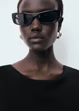 Vestido midi de corte recto y diseño minimalista, confeccionado en tejido elástico. Presenta cuello barco, tirantes anchos, espalda descubierta y una abertura posterior en el bajo.