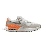Championes Nike Air Max Systm, con diseño de malla blanca y detalles en gamuza beige. Presenta el logo de Nike en gris y una unidad de aire visible en el talón con detalles en color naranja vibrante.