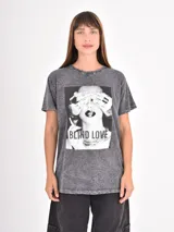 Remera de algodón con efecto acid wash en color gris oscuro, de corte holgado y manga corta. Presenta una estampa fotográfica en blanco y negro en el frente con la frase 'BLIND LOVE'.