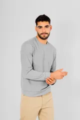 Buzo de manga larga color gris claro, con cuello redondo y detalle de costura en forma de V en la parte delantera del cuello. Presenta textura tipo waffle o panal de abeja.