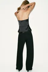 Top halter satinado negro con escote en V profundo, espalda descubierta, bajo en evasé con abertura frontal y cierre lateral con cremallera oculta.