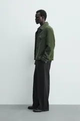 Sobrecamisa de hombre relaxed fit color verde oscuro, confeccionada en tejido de textura efecto toalla. Cuenta con cuello solapa, manga larga con puño abotonado, bolsillos de parche con solapa en el pecho, pespuntes a contraste y cierre frontal con botones.