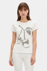 Remera manga corta blanca de algodón con elastano, corte ajustado al cuerpo, cuello redondo a la base y detalle de tachas metálicas en el cuello y las mangas. Cuenta con un estampado frontal grande de cerezas en tonos grises.